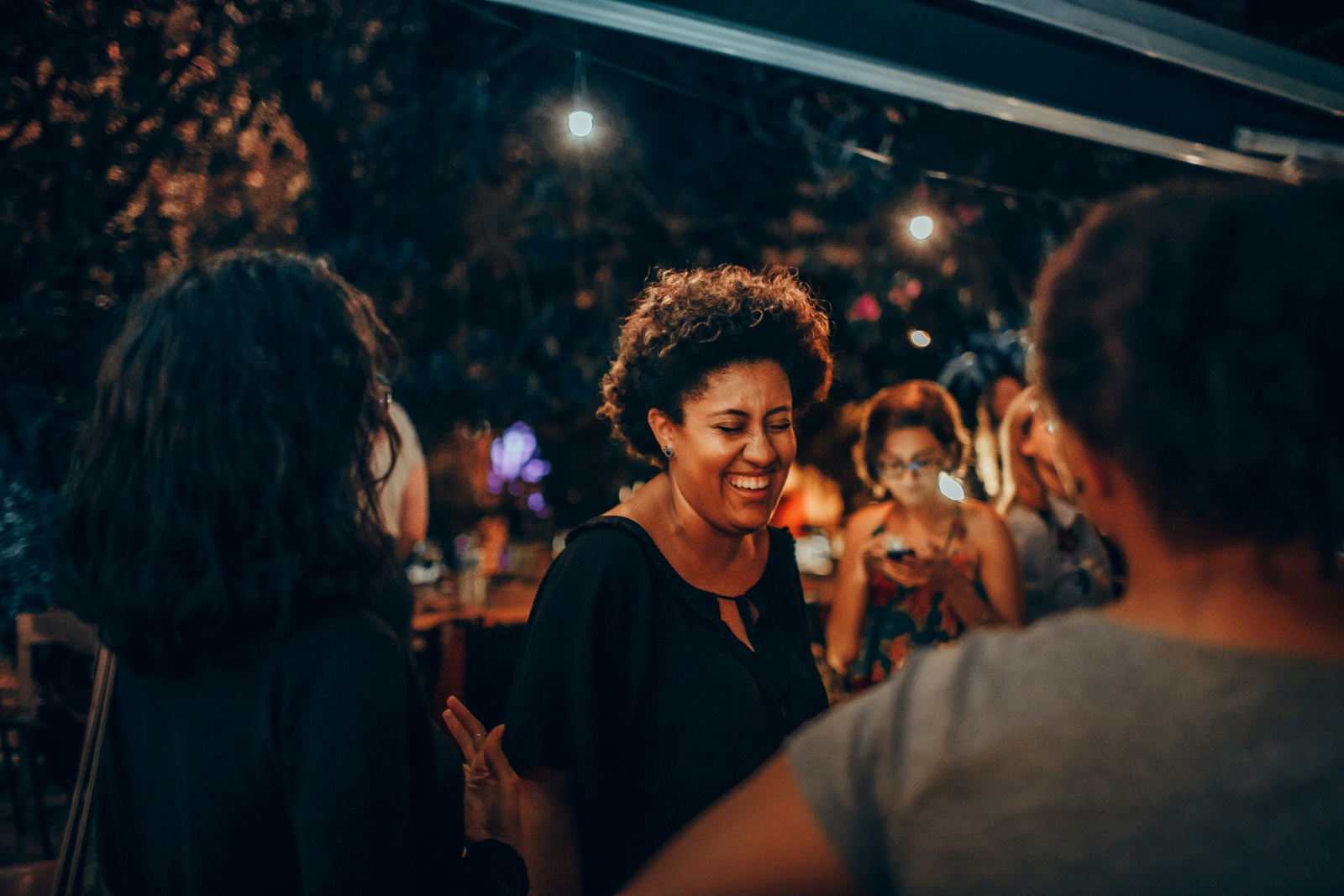 Woman laughing with friends at an evening dinner outdoors
